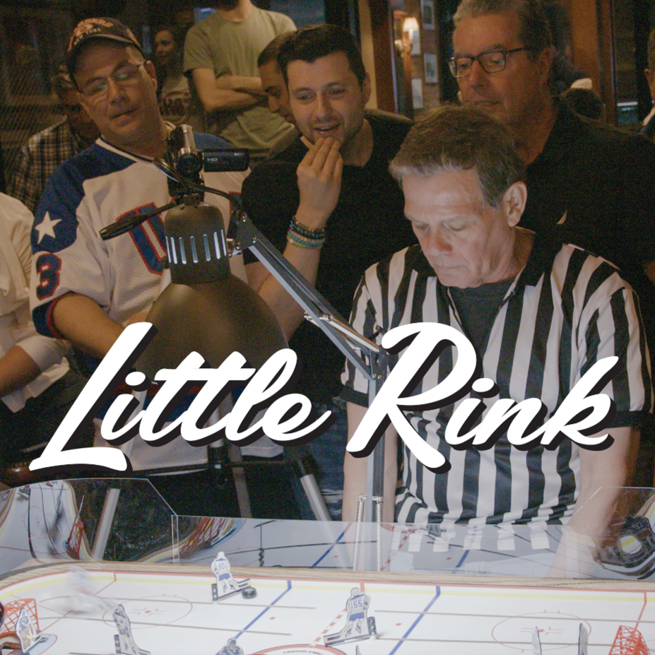 A referee and three men look down at a table hockey rink at a New York bar