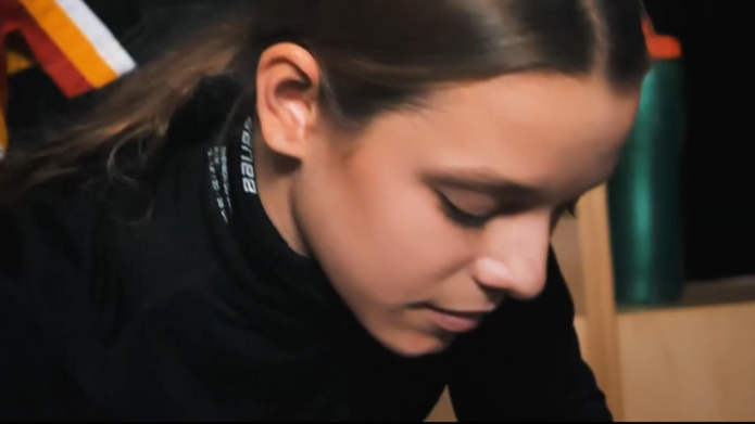 Photo of a young girl suiting up in hockey gear