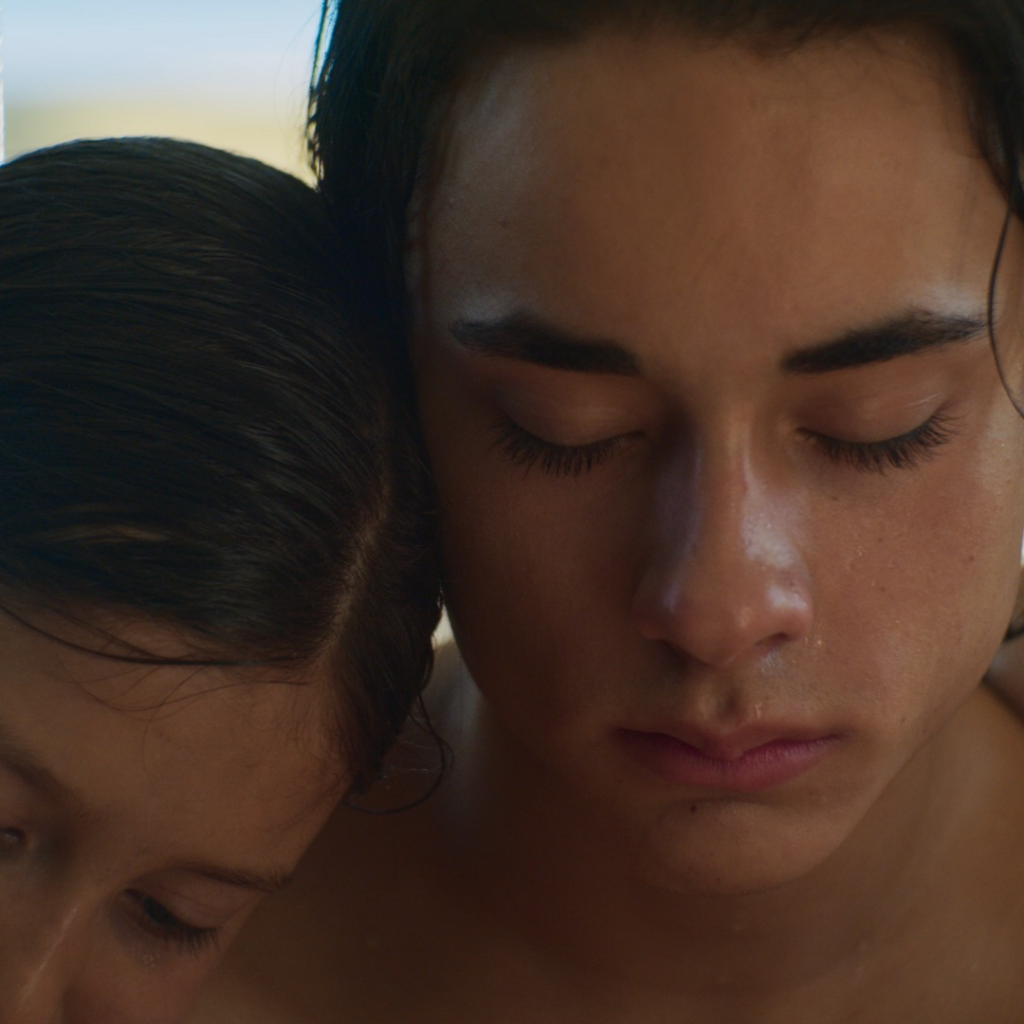 Close-up of two brothers with their arms around each other - both with wet hair at the pool. Square image from the fiction short film ‘Bleach’ by Canadian director Mattias Graham.