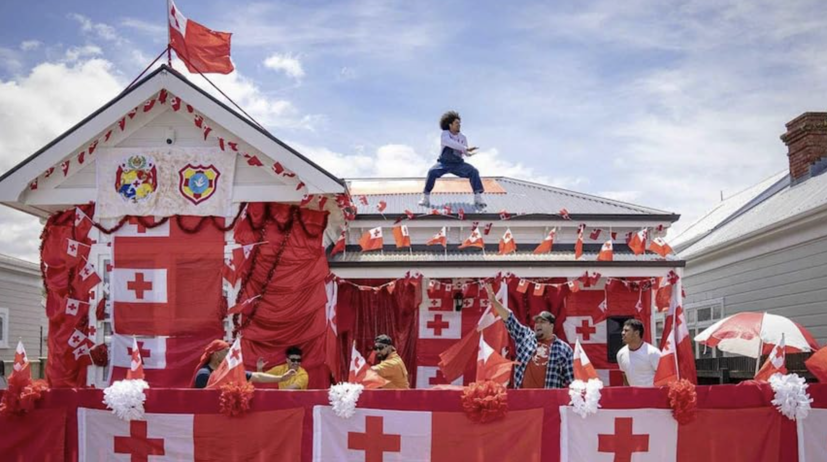 Image of a house covered in the red and white flags of Tonga